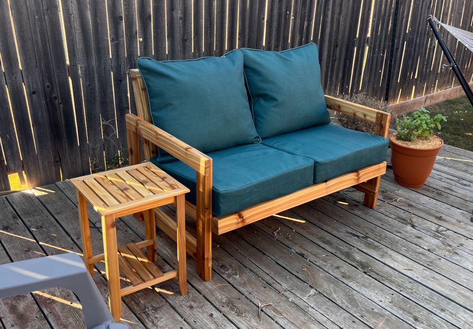 A photograph of a loveseat made with cedar with green cushions
