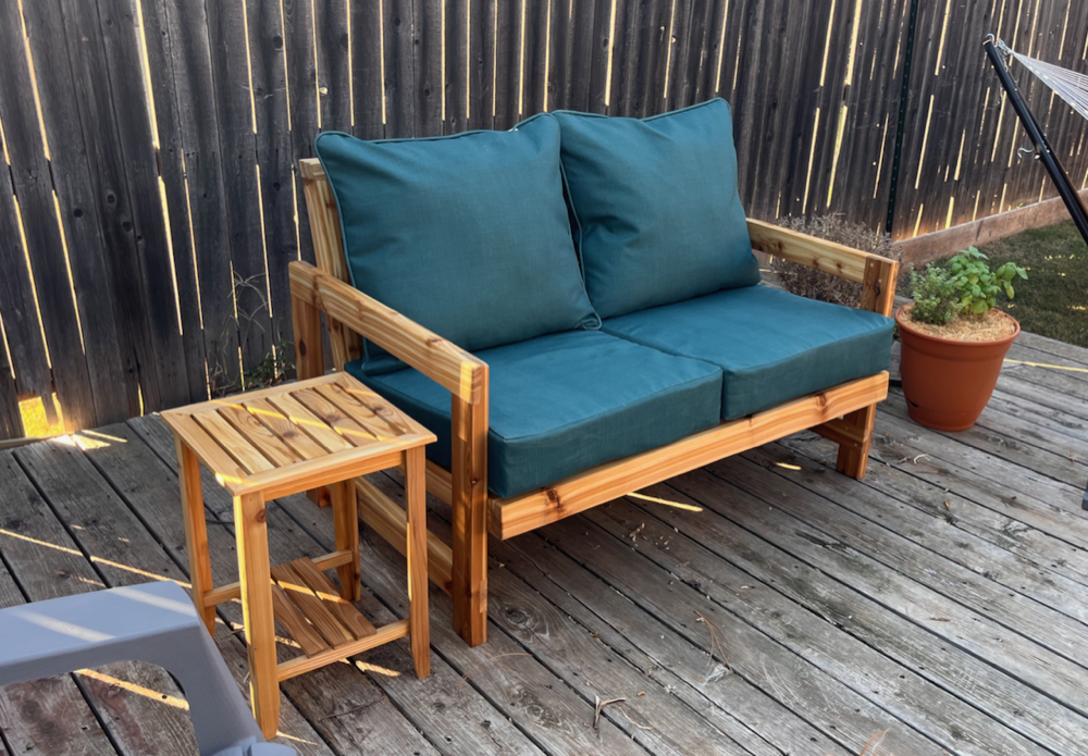 A photograph of a loveseat made with cedar with green cushions